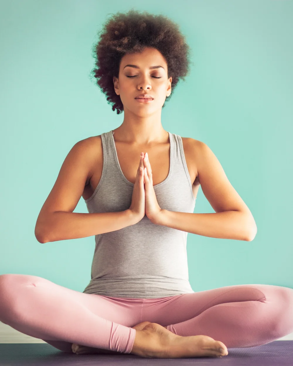 Woman meditating on a teal mat