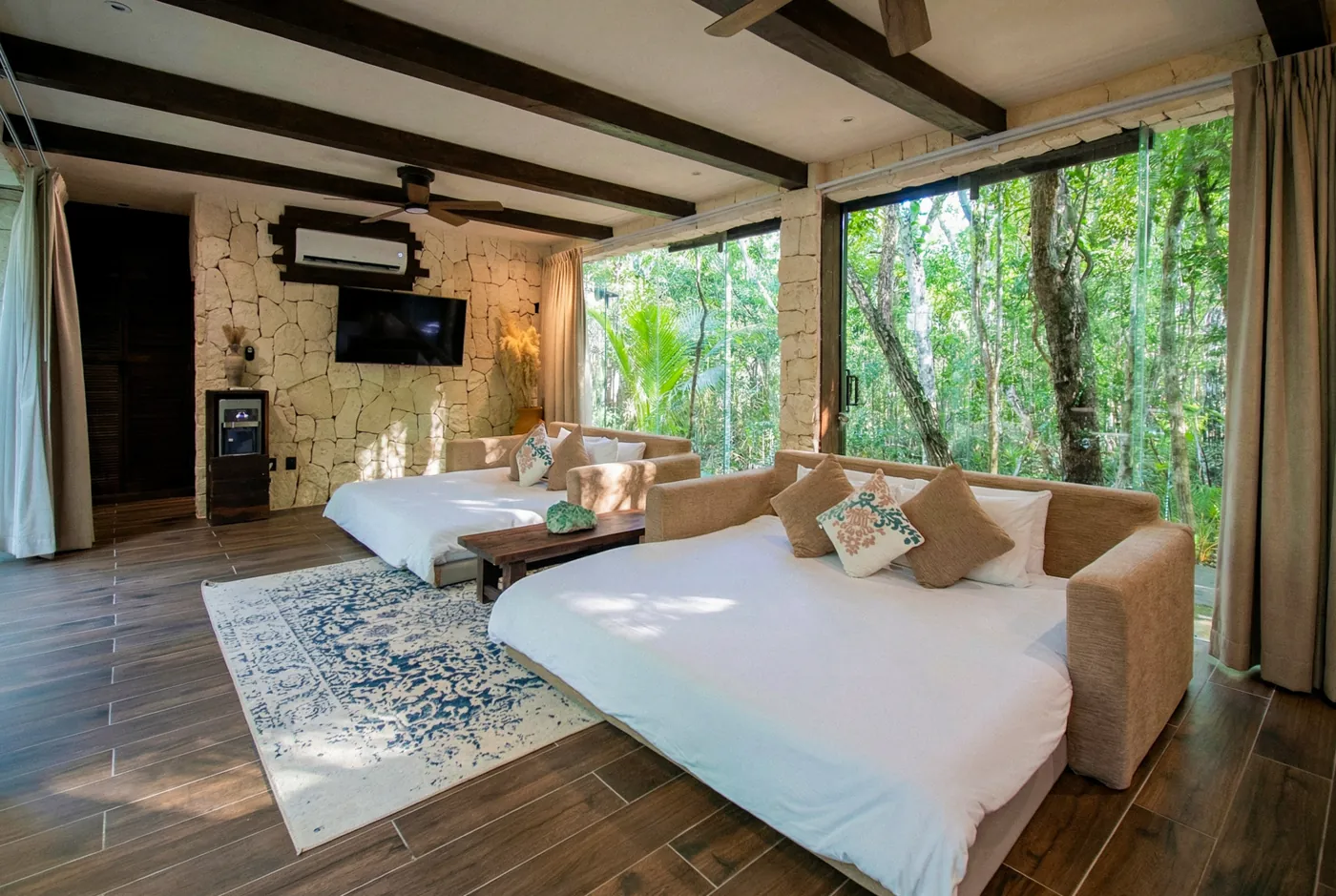Shared king suite at Kaaba Luum with two beds and a wall of windows onto the jungle